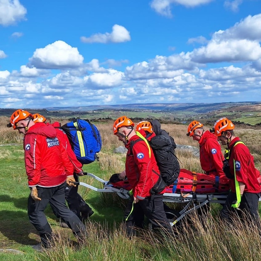 Six team members carrying a casualty on a stretcher.