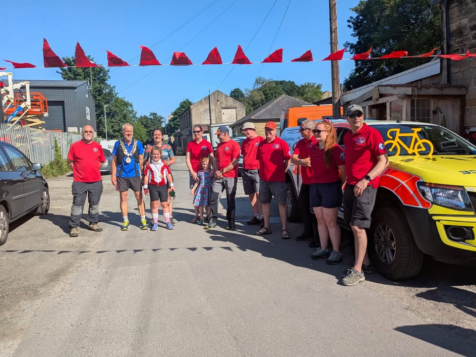 Group of Rescue volunteers celebrating Winnie completing her adventure, with red flags and vehicles in the background.