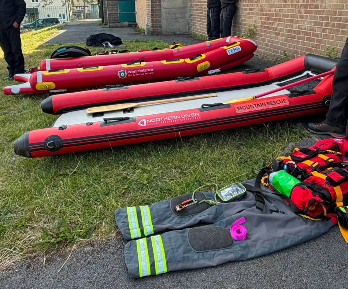 Two red inflatable rescue boats from Mountain Rescue are laid out on grass with rescue gear.